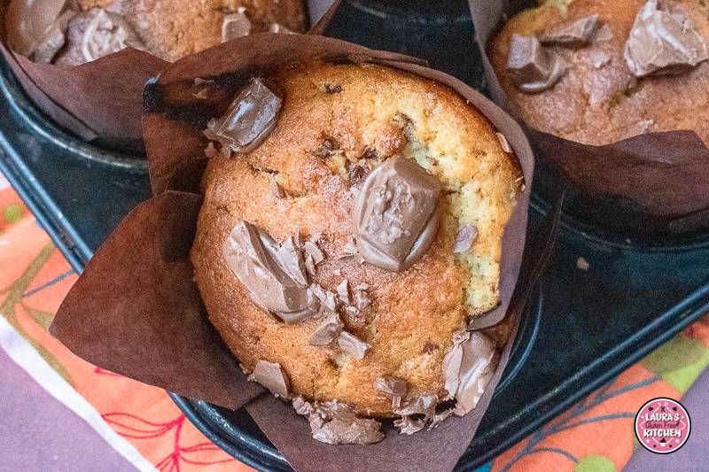 Close-up of moist chocolate chunk banana muffin with chopped chocolate on top.